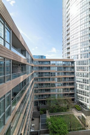 A multi-story building with a modern architectural design, featuring extensive glass facades and a courtyard with greenery. - Luxury Waterfront Escape Stylish 3BR Condo (Toronto)