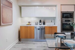 A modern kitchen with a dishwasher, a coffee maker, and a microwave. - Luxury Waterfront Escape Stylish 3BR Condo (Toronto)