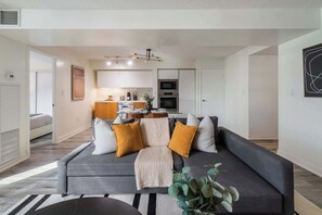 A modern living room with a grey sofa, a black coffee table, and a striped rug. - Luxury Waterfront Escape Stylish 3BR Condo | Parking Available (Toronto)