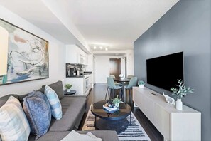 A modern living room with a sofa, coffee table, and artwork on the wall. - Downtown Central - Rogers Centre - 3 beds - Views (Toronto)