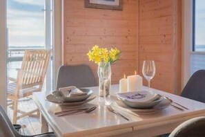 A dining table set with plates, cutlery, a vase with yellow flowers, and candles. - Hausboot The Goose - Fehmarn, Burgstaaken (Fehmarn)