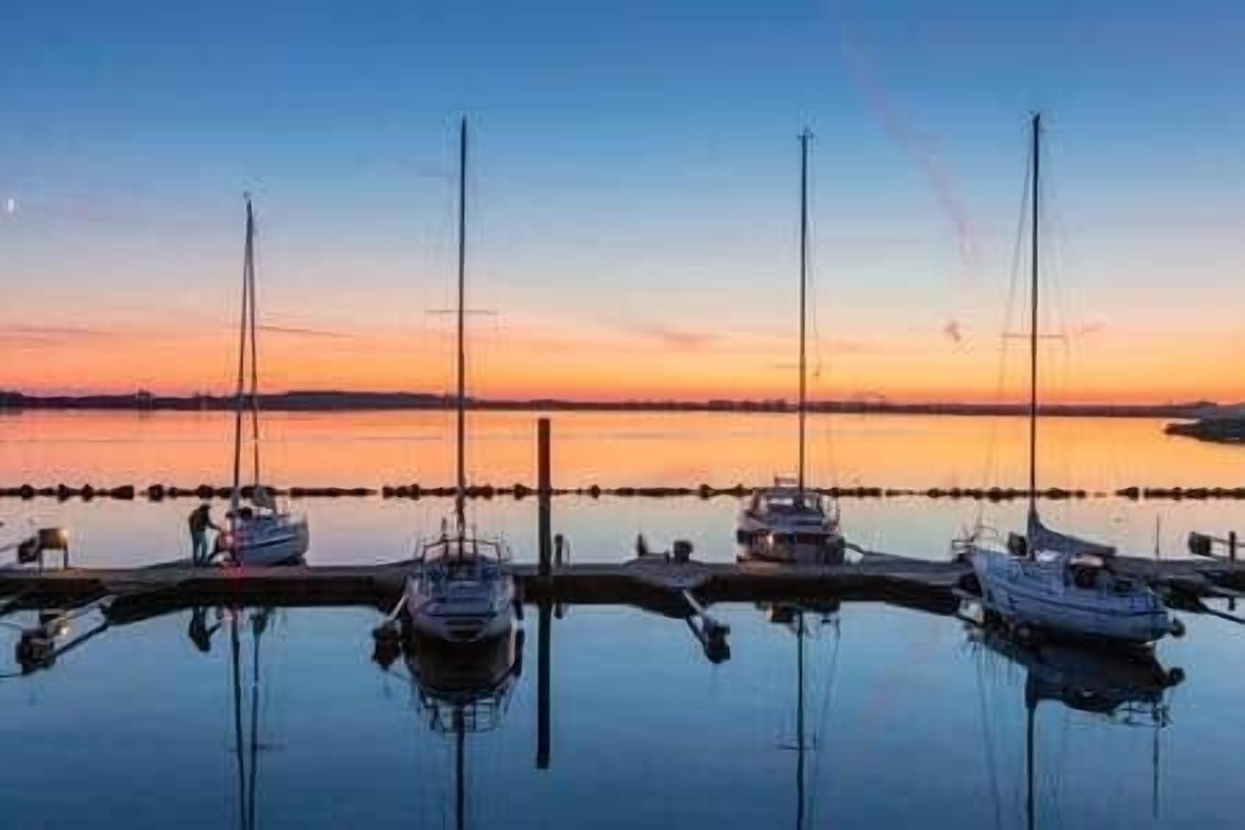 Ein Yachthafen mit vertäuten Booten im ruhigen Wasser bei Sonnenuntergang.