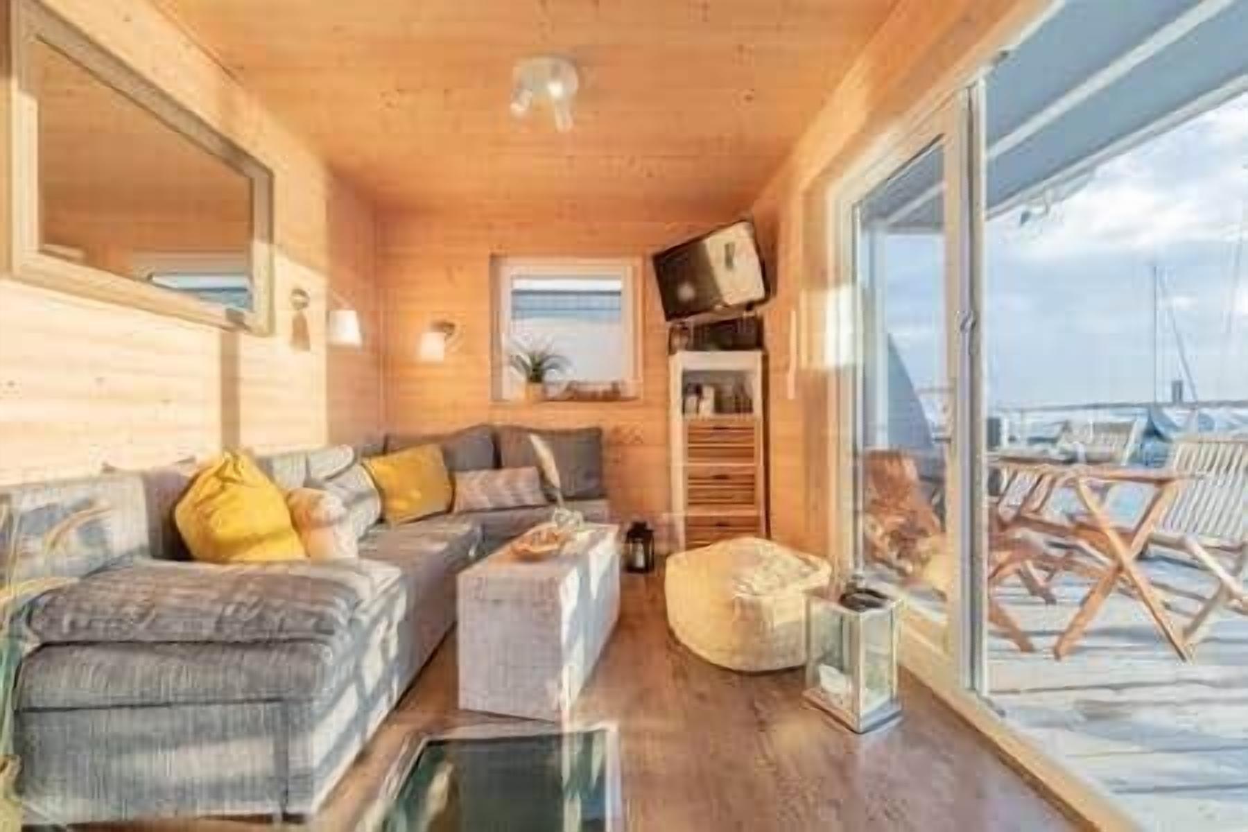 A wooden interior with a sofa, ottoman, and a television.