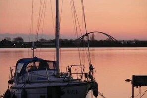 Un voilier est amarré sur une étendue d’eau calme, au moment du coucher du soleil.