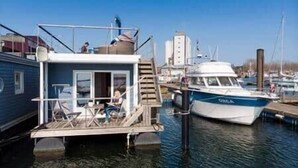 A floating structure with a deck, a staircase, and a small enclosed area with seating. - Bosse Houseboat - Fehmarn, Burgstaaken (Fehmarn)