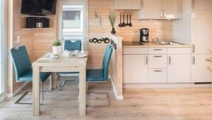 A compact kitchen with a dining area, wooden flooring, and a television mounted above the counter. - Bosse Houseboat - Fehmarn, Burgstaaken (Fehmarn)