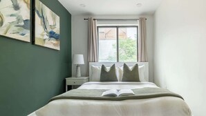 A bedroom with a bed, a nightstand, a lamp, and two abstract paintings on the wall.