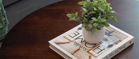 Ein runder Couchtisch aus Holz mit einer Topfpflanze und einem Buch mit dem Titel 'Love Home'.