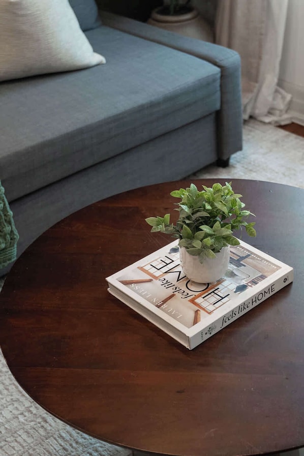 Una mesa redonda de madera con una planta en maceta y un libro titulado 'Love Home'.