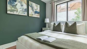 A bedroom with a bed, a nightstand, a lamp, and two abstract paintings on the wall.