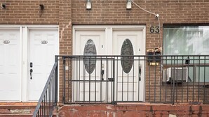 A two-story brick building with numbered garage doors, a metal staircase, and a small balcony with a railing.