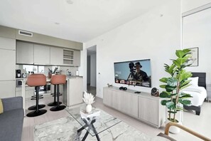 A modern living room with a TV, seating, and a plant. - Luxury 2BR Suite in Heart of Toronto Entertainment | Parking Available (Toronto)