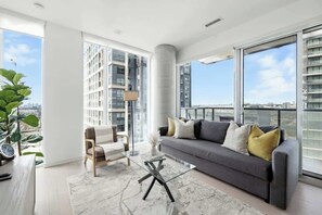 A modern living room with a sofa, coffee table, and a large window offering a city view. - Luxury 2BR Suite in Heart of Toronto Entertainment | Parking Available (Toronto)