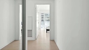 Ein Flur mit einer Tür zu einem Zimmer mit einem Bett und einem Fenster.