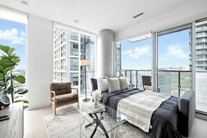 A modern bedroom with a large bed, a sofa, a coffee table, and a view of the city. - Luxury 2BR Suite in Heart of Toronto Entertainment | Parking Available (Toronto)
