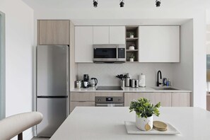 A modern kitchen with a stainless steel refrigerator, a microwave, and a coffee maker on the countertop.