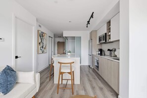 A modern kitchen with a central island, wooden cabinets, and a microwave.