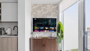 A modern living room with a flat-screen TV mounted on a wall displaying a streaming service interface.