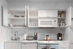A modern kitchen with white cabinetry, a microwave, a coffee maker, and a gas stove. - Free Parking! Grand 3BR/2BA Suite | Sleeps 8 | Parking Available (Toronto)