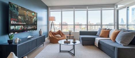 A modern living room with a large flat-screen TV, a sofa, a coffee table, and a bean bag chair.