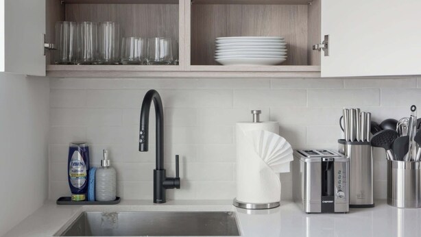 A modern kitchen with a built-in sink, a stainless steel toaster, and a set of knives in a holder.