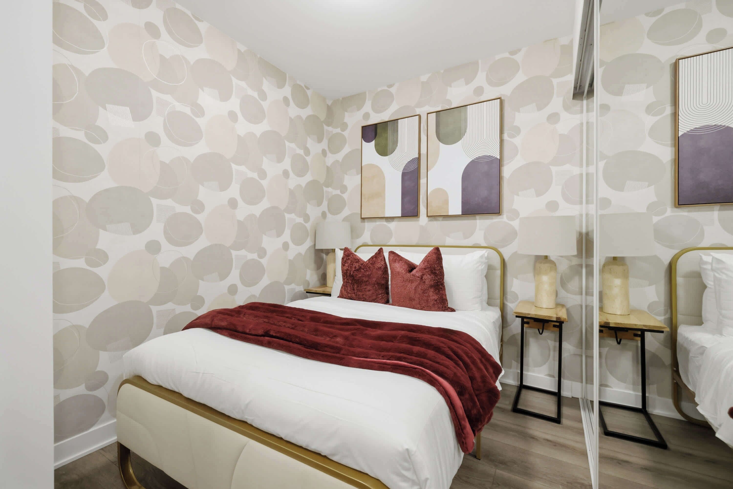A hotel room with a bed, a nightstand, a lamp, and artwork on the wall.