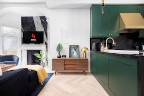 A modern living room with a fireplace, a television mounted on the wall, and a sofa.
