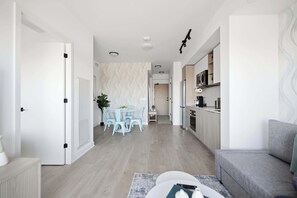 A modern apartment with a dining area, kitchen, and living room. - Bright Condo, Skyline Views & Balcony | Parking (Toronto)