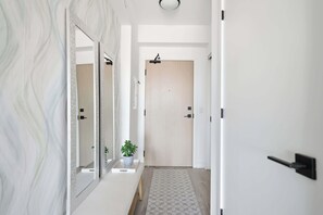 Um corredor com parede de mármore, uma planta em vaso e um tapete estampado.