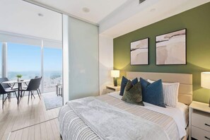 A modern hotel room with a large bed, a dining area, and a balcony with a city view. - Downtown 1BR Urban Comfort Steps from it All (Toronto)