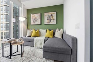 A modern living room with a grey sofa, a small round table, and abstract art on the wall. - Downtown 1BR Urban Comfort Steps from it All (Toronto)