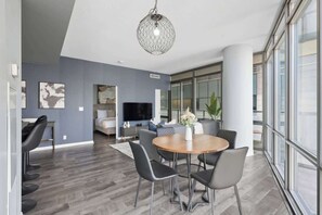 A modern living room with a dining area, large windows, and a television.
