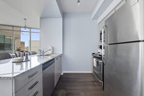 A modern kitchen with a stainless steel refrigerator, built-in oven, and a marble countertop. - Designer Skyline Retreat 2BR w Skyline Terrace! (Toronto)