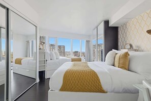 Une chambre d’hôtel avec un grand lit, un lit plus petit, un dressing et une vue sur la ville.