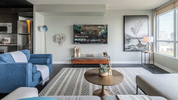 A modern living room with a sofa, coffee table, and artwork on the wall. - Elevated Downtown Living Luxe 3BR w Views! (Toronto)