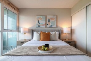 A hotel room with a large bed, two bedside lamps, a tray with artichokes, and abstract paintings on the wall. - Elevated Downtown 3BR w Views & Free Parking (Toronto)