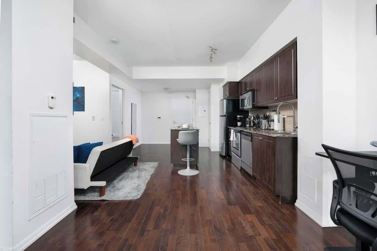 A modern kitchen with dark wooden cabinets, stainless steel appliances, and a bar stool.