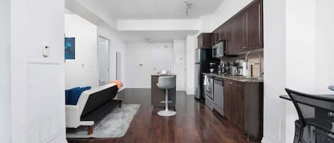 A modern kitchen with dark wooden cabinets, stainless steel appliances, and a bar stool.