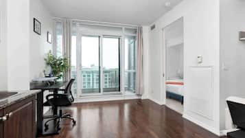 A modern apartment with a kitchen area, a dining table, and a large sliding glass door leading to a balcony.