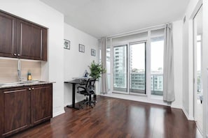 A modern kitchen with dark wood cabinets, a countertop, and a window with a view of buildings.