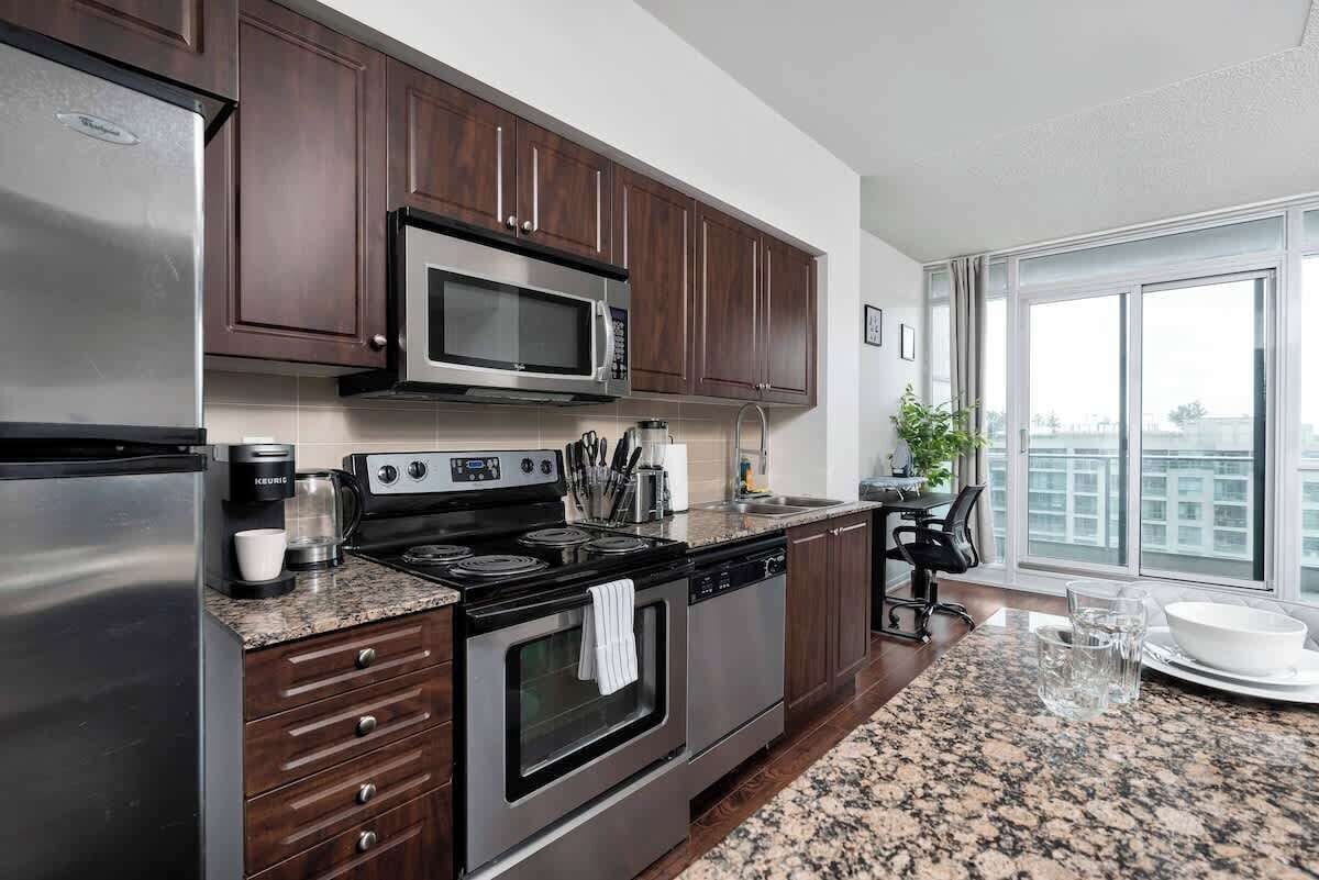 A modern kitchen with dark wood cabinets, stainless steel appliances, and a granite countertop.