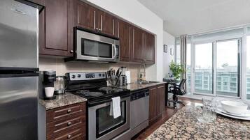 A modern kitchen with dark wood cabinets, stainless steel appliances, and a granite countertop.