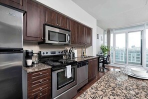 A modern kitchen with dark wood cabinets, stainless steel appliances, and a granite countertop.