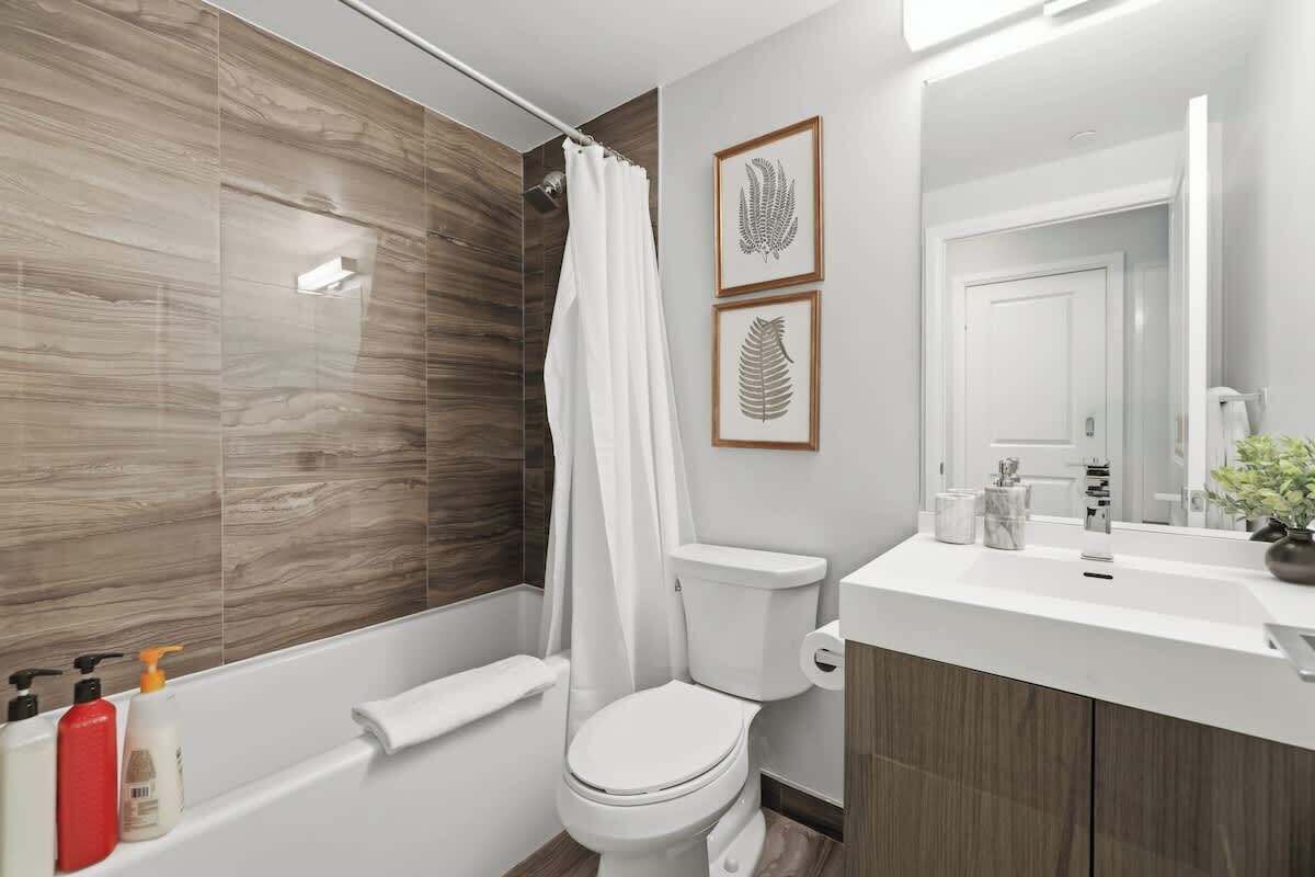 A modern bathroom with a bathtub, toilet, and vanity.