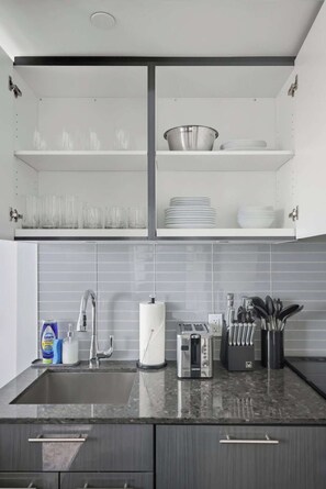 A modern kitchen with a built-in sink, a toaster, and a knife block. - Chic Downtown Oasis Steps to Yonge & Dundas | Parking Available (Toronto)
