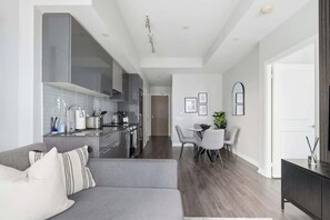 Eine moderne Küche mit Essbereich, grauem Sofa und einem kleinen Tisch mit Stühlen.