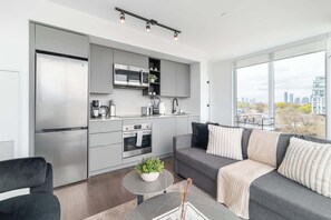 Una cocina moderna con electrodomésticos integrados, un comedor con mesa redonda y un sofá con cojines decorativos.