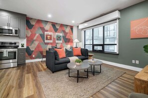 A modern kitchen with stainless steel appliances and a dining area with a sofa and coffee table. - Artful Downtown Toronto Retreat,  King Bed, 55" TV | Parking Available (Toronto)
