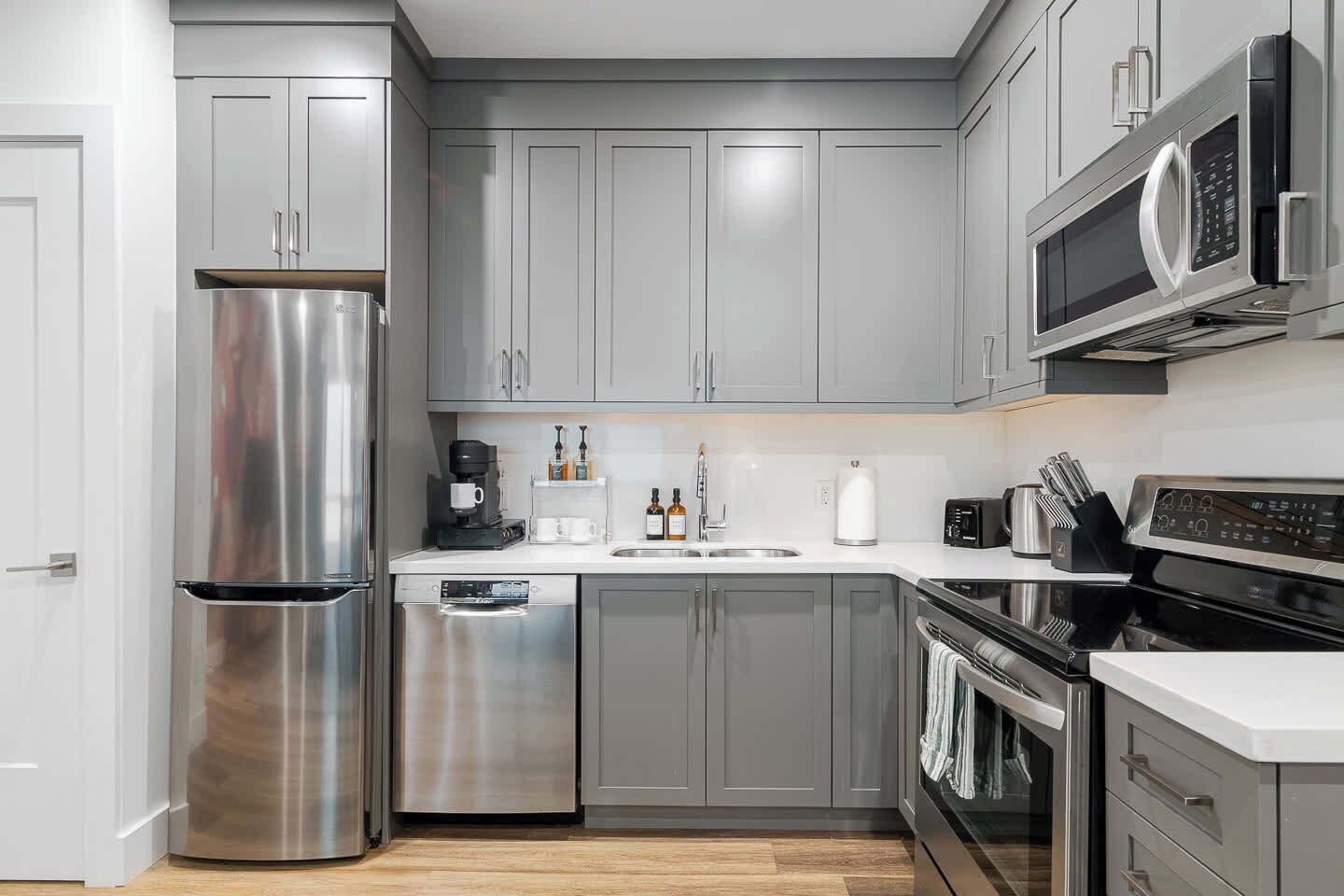 Una cocina moderna con electrodomésticos de acero inoxidable, gabinetes grises y microondas integrado.