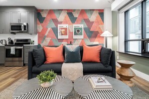 A modern living room with a sofa, a coffee table, and a kitchen area in the background. - Artful Downtown Toronto Retreat,  King Bed, 55" TV | Parking Available (Toronto)